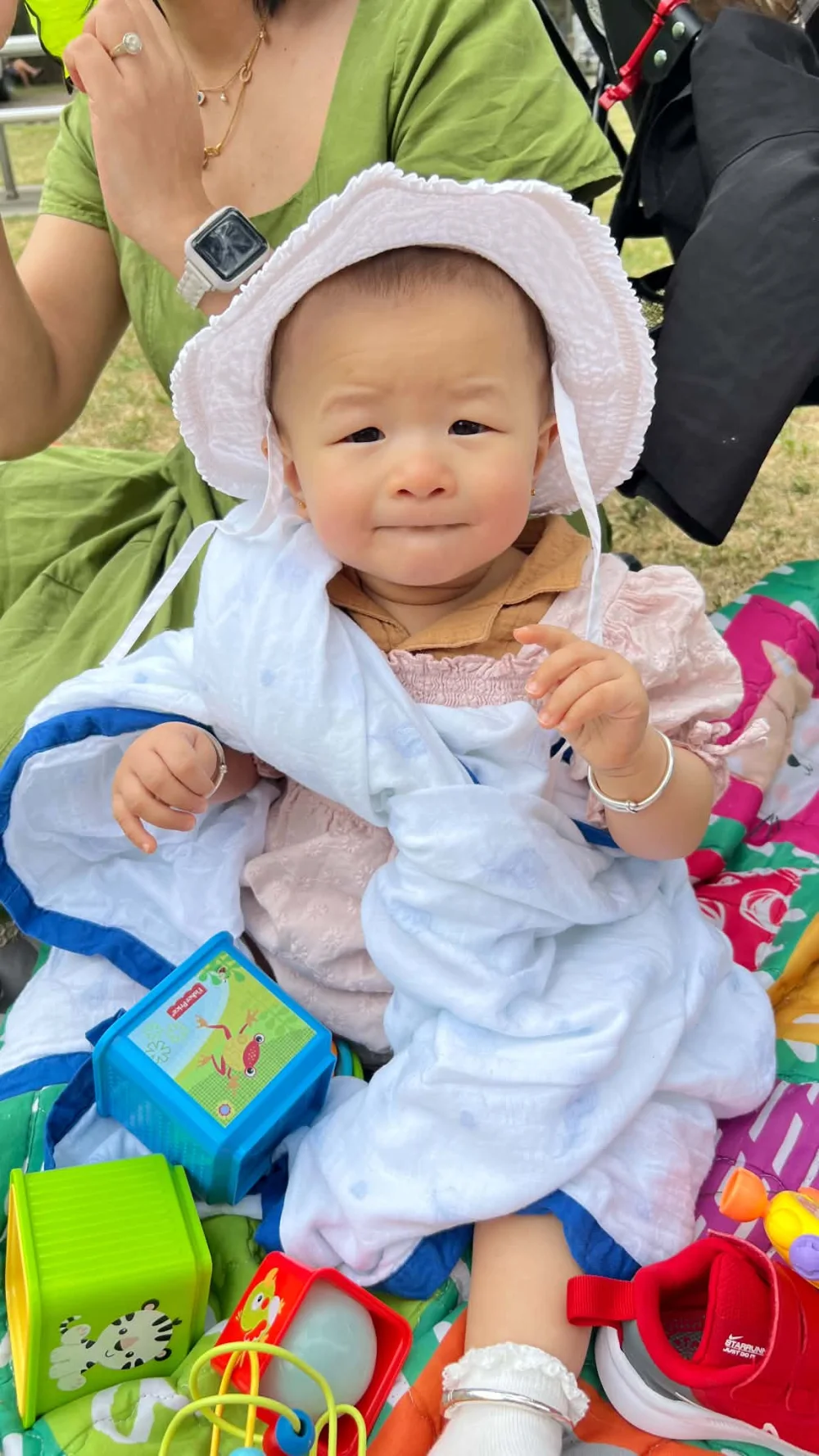 Aira outdoors in a white sunhat among her toys